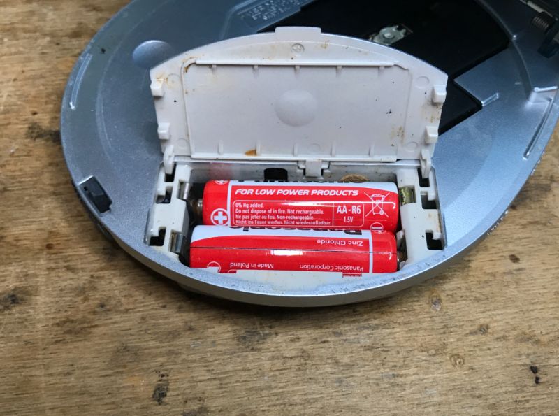 Battery Compartment with Two AA-R6 Batteries Battery compartment with two red AA-R6 batteries, partially covered by an open flap.