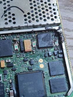 Wnętrze urządzenia elektronicznego z widocznymi uszkodzeniami i korozją na płycie głównej.