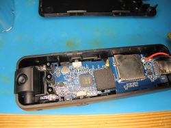 Disassembled electronic device with camera and PCB components Interior of electronic device with PCB, camera module, and microSD slot