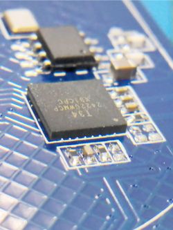 Close-up of a microchip and components on a blue PCB circuit board