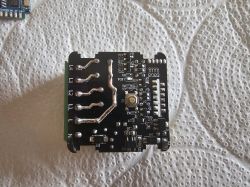 Electronic module with button and labeled pins on a black PCB