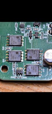 Zbliżenie na płytkę drukowaną z kilkoma układami scalonymi i innymi elementami elektronicznymi.