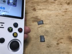 Left side of R36S handheld console with buttons and two microSD cards on wooden surface