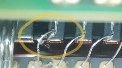 Zbliżenie na elementy elektroniki z drucikami bondingu; jedna sekcja zaznaczona żółtym okręgiem