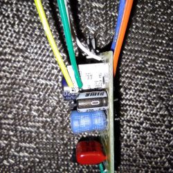 Close-up of a circuit board with soldered capacitors and colored wires.