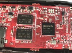 Red PCB close-up with Rockchip RK3036S chip and two memory ICs beside an edge connector