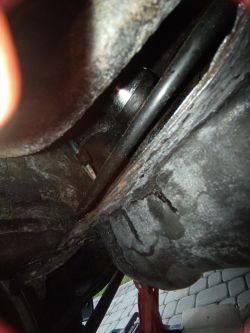 Close-up of the underside of a metal fuel tank with visible sealing and corrosion protection marks.