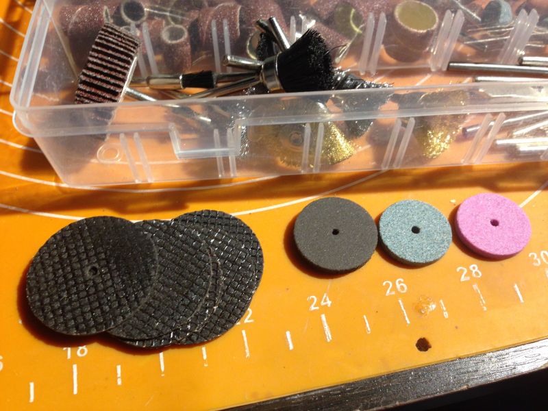 Zestaw tarcz szlifierskich i akcesoriów w pojemniku.