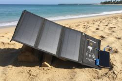 Solar panel on wooden stand at the beach, connected to smartphone