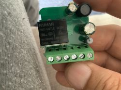 Printed circuit board in hand, featuring a FANHAR FH17-1A2TLE relay and several capacitors.