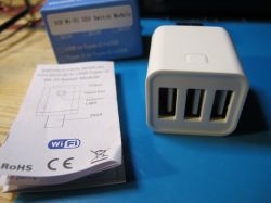 White Wi-Fi USB module with three ports on a blue background, next to a user manual.