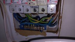 Widok rozdzielni elektrycznej z różnymi przewodami i zabezpieczeniami, w tym złączem typu Róża Wiatrów.
