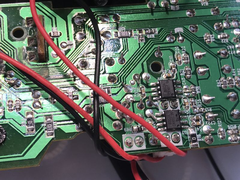 Underside of a green PCB with solder joints, traces, two 8002A chips, and red and black wires crossing