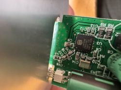 Close-up of a green printed circuit board with IC chip and capacitors visible