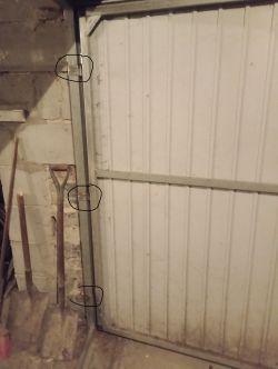 Zbliżenie na metalową bramę z trzema zaznaczonymi zawiasami profilowymi