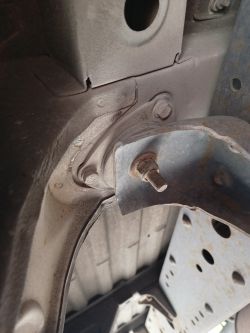Fragment tylnego wspornika kabiny z przynitowanym mocowaniem w Iveco Daily furgon, widoczne elementy poduszek i śruba.