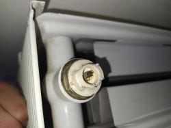Zbliżenie na zawór odpowietrzający grzejnika z białą plastikową obudową