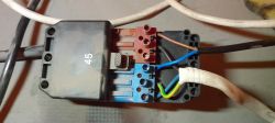Zbliżenie na moduł elektryczny z podłączonymi przewodami brązowym, niebieskim i żółto-zielonym