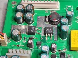 Fragment wnętrza switcha sieciowego z widocznymi elementami elektronicznymi, w tym kondensatorami, tranzystorami i baterią litową.