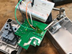Green PCB with soldered wires connected to a breadboard on a workbench