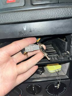 Zbliżenie na wtyczkę antenową i adapter w ręku na tle konsoli środkowej Golfa MK4