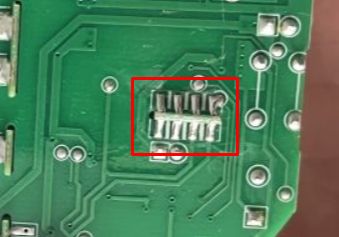 Close-up of a printed circuit board with a black transistor highlighted by a red rectangle.