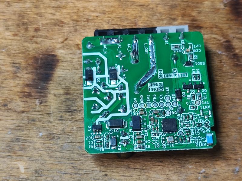 Inside the Sonoff ZBMini Interior of Sonoff ZBMini printed circuit board on a wooden surface.
