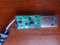 Obwód elektroniczny z wtyczką USB i okablowaniem na drewnianym tle.