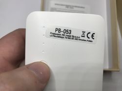 Zbliżenie na biały powerbank PB-053 z etykietą producenta i trzema diodami LED.