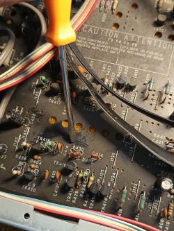 Wnętrze uszkodzonego wzmacniacza Denon, widoczny śrubokręt i elementy elektroniczne.