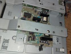 Wnętrze urządzenia elektronicznego z widoczną płytą główną i osłonami metalowymi