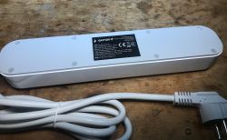 White Gembird TSL-PS-F4U-01-W power strip, bottom side up, with technical label, power cord, and plug visible.