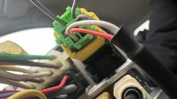 Close-up of a car's electrical wiring with a green and yellow connector inside the vehicle.