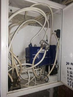 Widok na szafkę elektryczną z chaotycznymi kablami i splitterem.