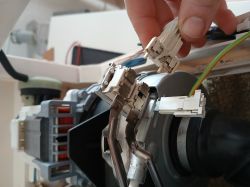 Zbliżenie na uszkodzony przewód z końcówką przy module grzewczym zmywarki