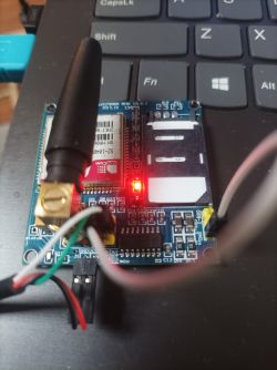 Konwerter USB-UART podłączony do laptopa z widocznymi przewodami i czerwoną diodą.