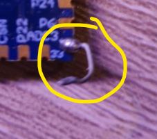 Soldered electronic component on a blue PCB with a protruding wire.