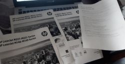 Wydrukowane instrukcje HP LaserJet leżące na laptopie marki ASUS