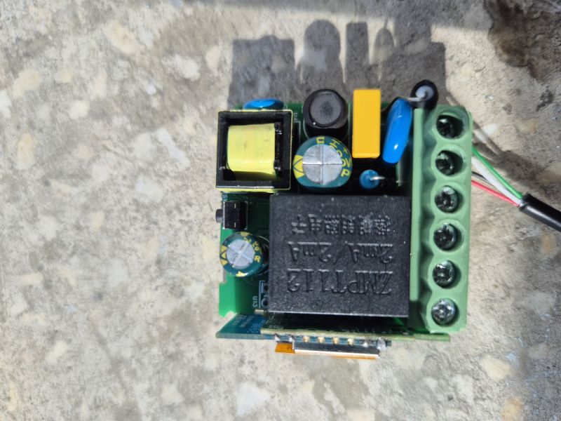 Circuit board with black relay, green screw terminal block, and power components on a concrete surface
