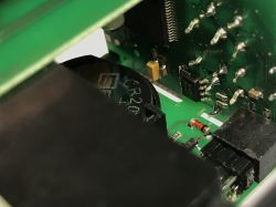 Zbliżenie na płytkę drukowaną z widocznymi elementami elektronicznymi, baterią CR2032 oraz złączami.