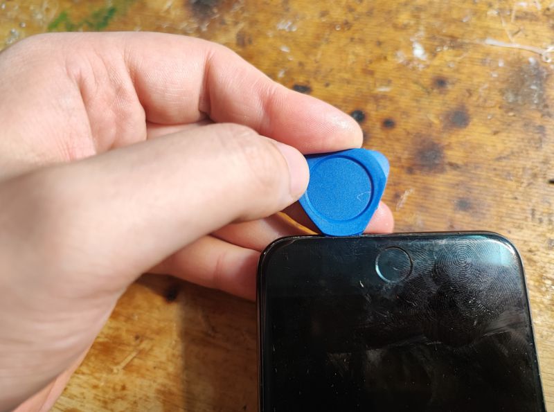 Prying Open iPhone Screen with a Guitar Pick A person uses a blue guitar pick to pry open an iPhone screen.