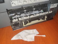 Cleaning a Brother Printer Open Brother printer with visible internal mechanism, a cotton swab and a lint-free cloth lying nearby.