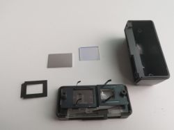 Elementy wizjera aparatu Polaroid Automatic 104 Land Camera rozłożone na części.