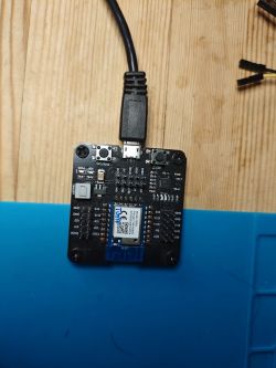 Electronic board with a connected USB cable on a wooden table.