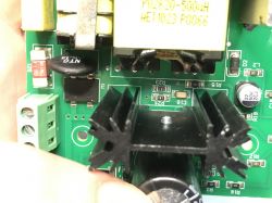 Close-up of a printed circuit board with electronic components, visible heatsink, capacitors, and terminal block.