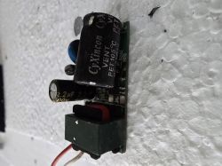 Uszkodzony moduł z urwanymi przewodami zasilającymi Moduł elektroniczny z kondensatorami i urwanymi przewodami brązowym i niebieskim