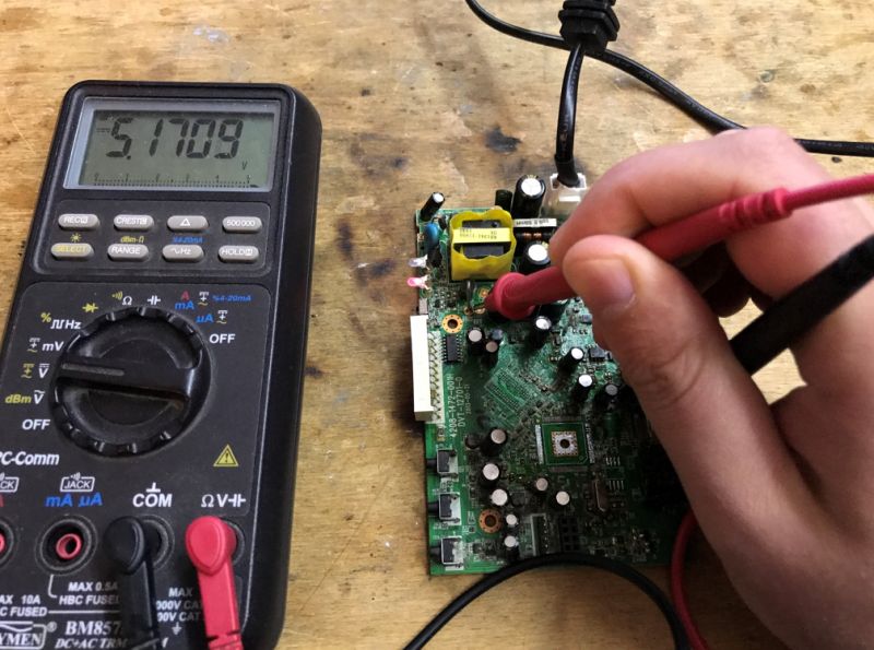 Voltage Measurement on Motherboard with Multimeter Person measuring voltage on a motherboard with a multimeter.