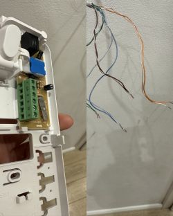 Zbliżenie na otwartą białą obudowę elektroniki i wystające ze ściany kable.