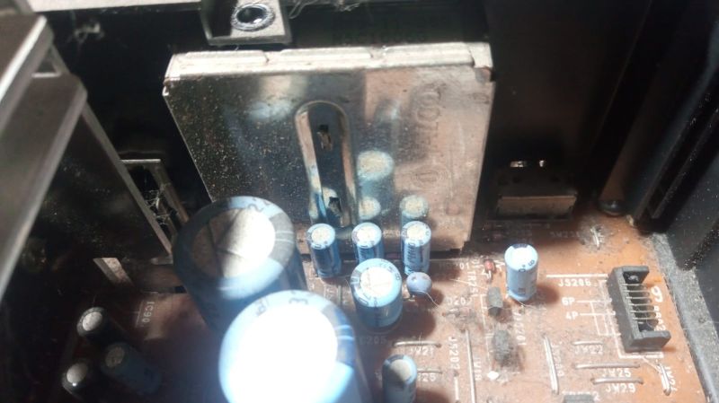 Zbliżenie na zakurzoną płytkę z kondensatorami elektrolitycznymi i modulatorem RF.
