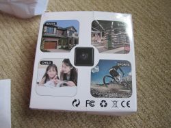 Mini spy camera packaging with usage illustrations Packaging of a mini spy camera showing four example uses: house, shop, child, and sports.